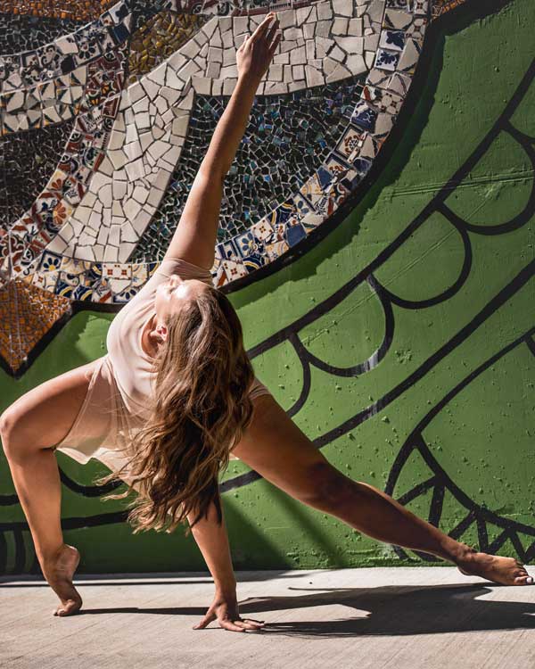 graceful dancer in flowing costume posing in front of giant mosaic